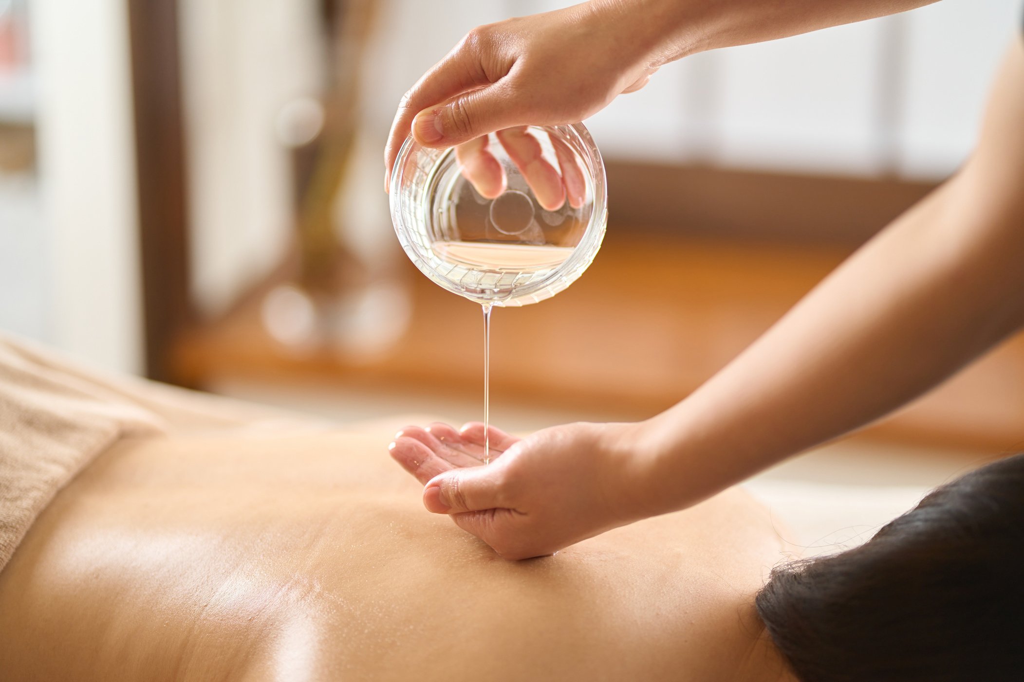 Esthetician dripping massage oil at beauty salon